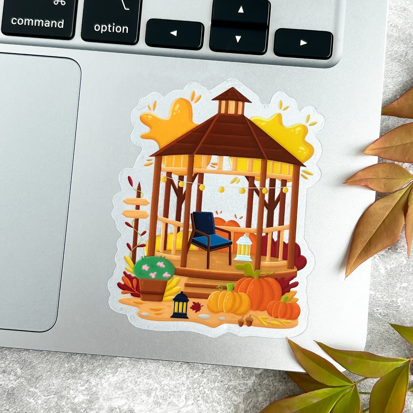 Sticker of a gazebo with pumpkins and autumn leaves on a laptop.