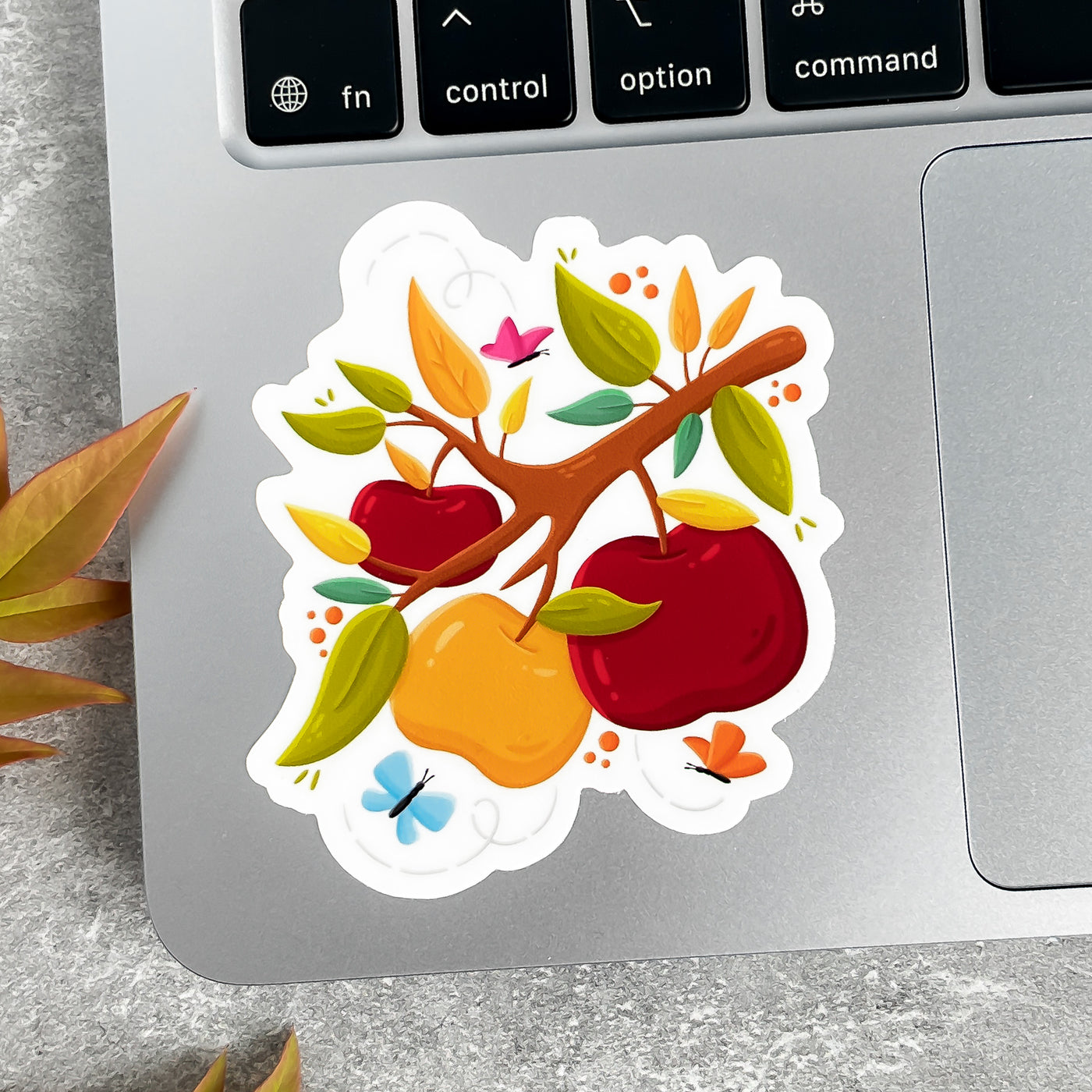 Colorful sticker of apples and leaves on a laptop keyboard.