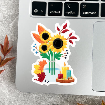Decorative sticker with sunflowers and candles on a laptop keyboard.