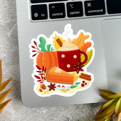 Sticker with pumpkins, a mug, and pie on a laptop keyboard.