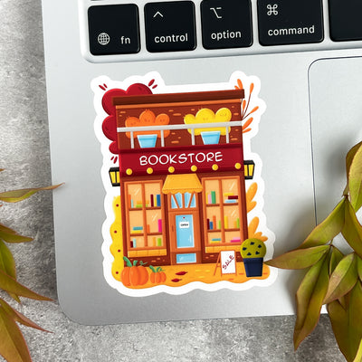 Sticker of a bookstore on a laptop keyboard with plants around.