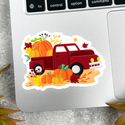Sticker of a red truck with pumpkins on a laptop.