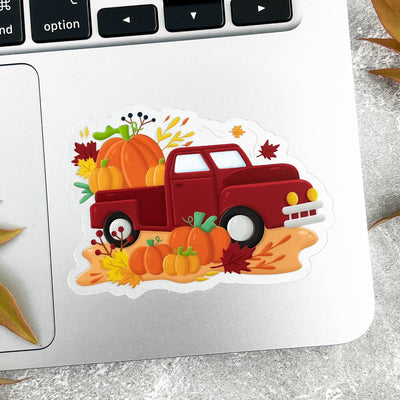 Sticker of a red truck with pumpkins on a laptop.