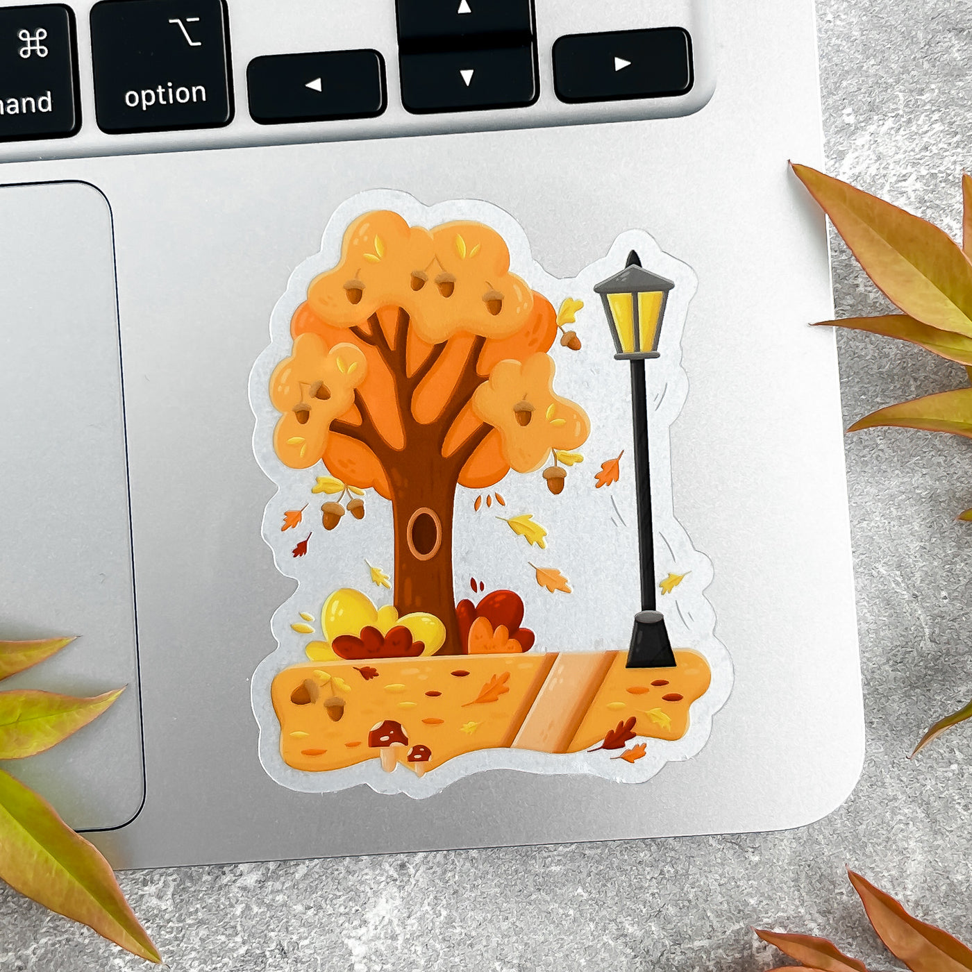 Autumn-themed sticker with tree and lamp post on a laptop.