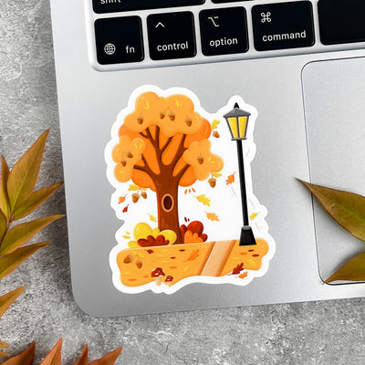 Autumn-themed sticker on a laptop with leaves around.