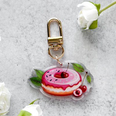 Keychain with a donut design on a gray surface with flowers.