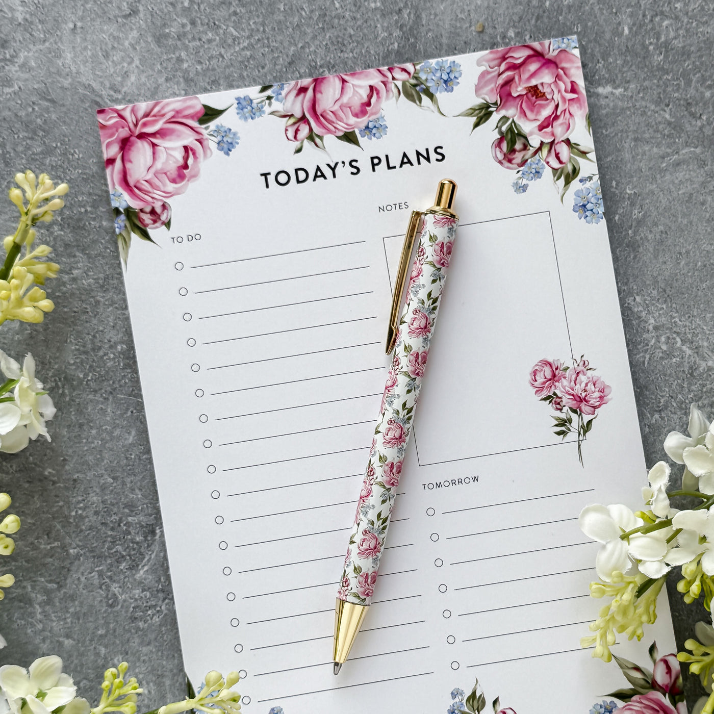 Floral planner with pen on a gray surface with flowers