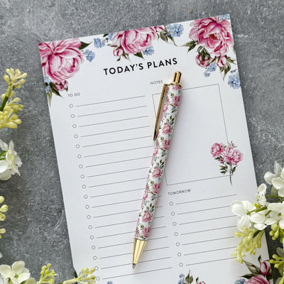 Floral planner with pen on a gray surface with flowers
