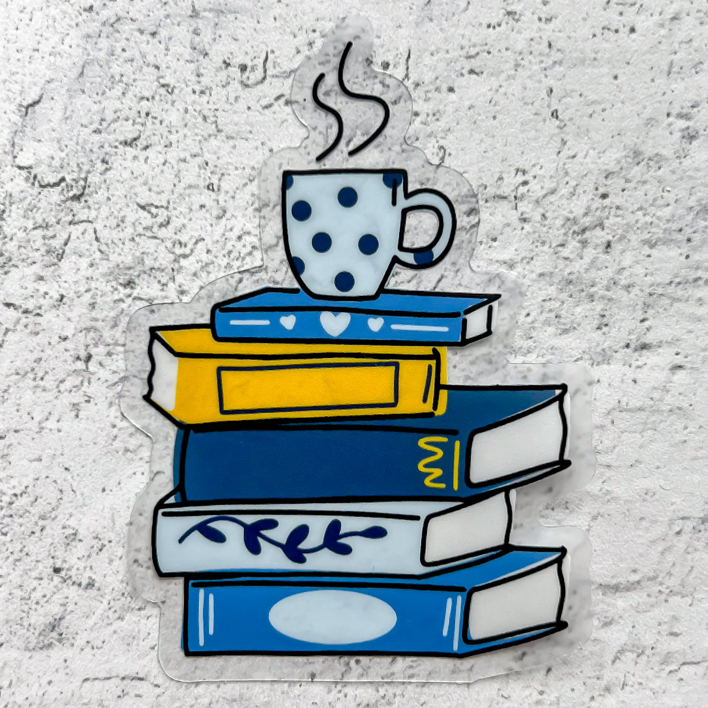 Stack of yellow and blue books with a mug on top. Clear vinyl waterproof sticker.