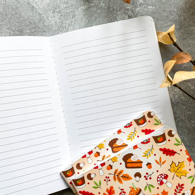 Notebook with a decorative fall-themed cover on a textured surface.